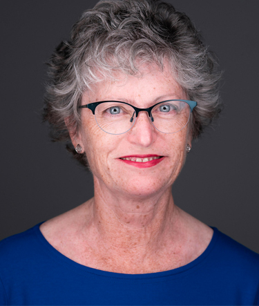 A woman with glasses is smiling for the camera.